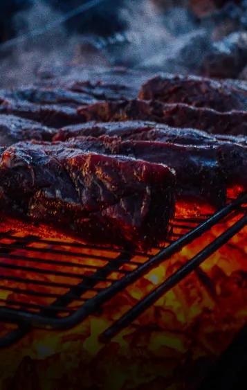 steaks cooking on a grill with flames