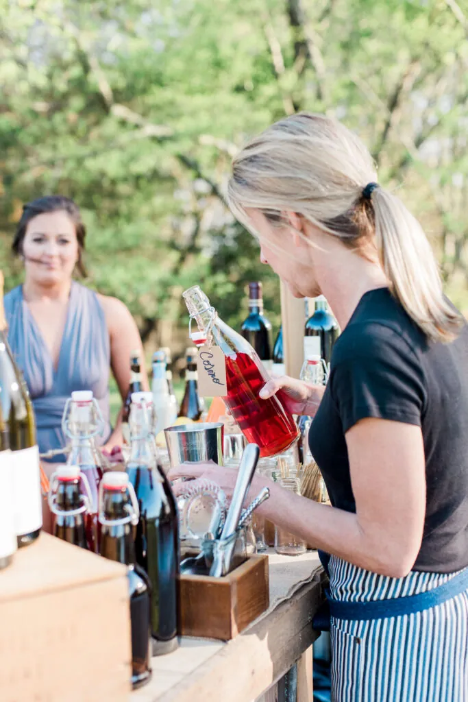 a woman standing at a table filled with bottles of wine